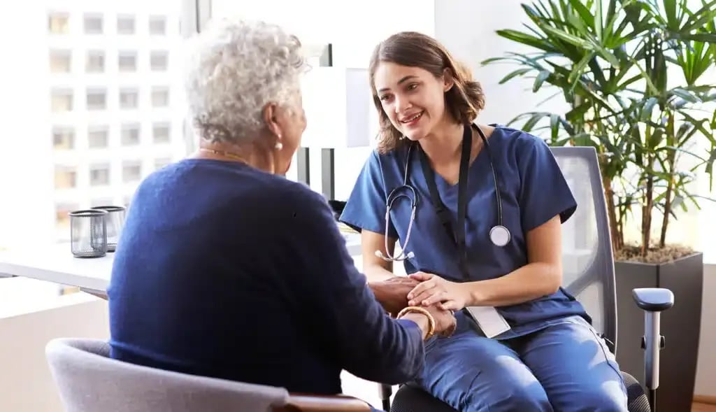 A-young-nurse-talking-to-an-elderly-patient-in-an-office-reassuring-her-with-a-gentle-smile-while-placing-her-hand-on-the-patientΓCOs-hand.jpg-1024x589.jpg